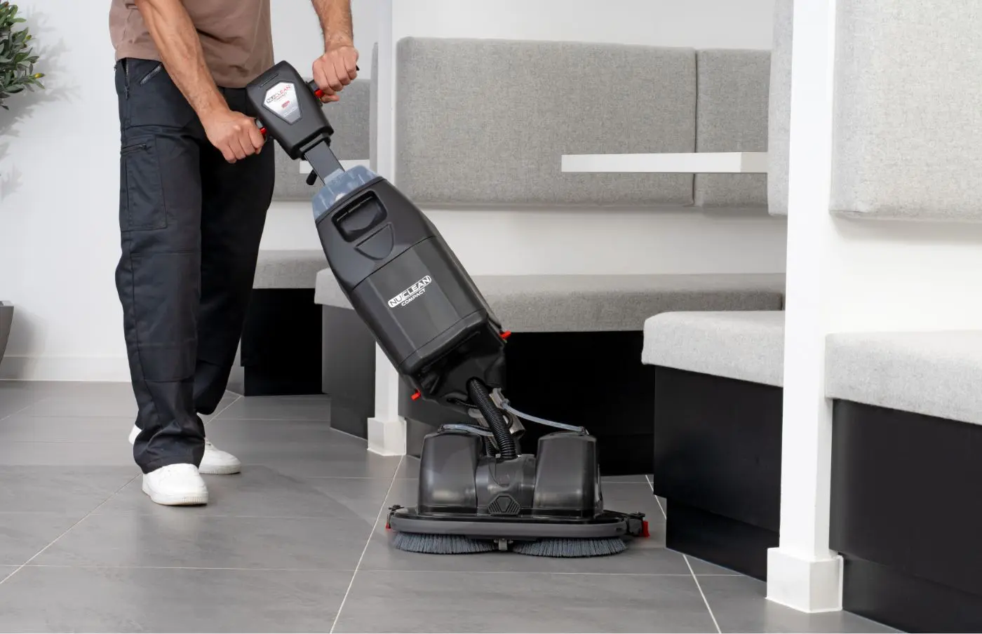 Person manoeuvring Numatic 440NX Flex scrubber dryer around a table in a modern office